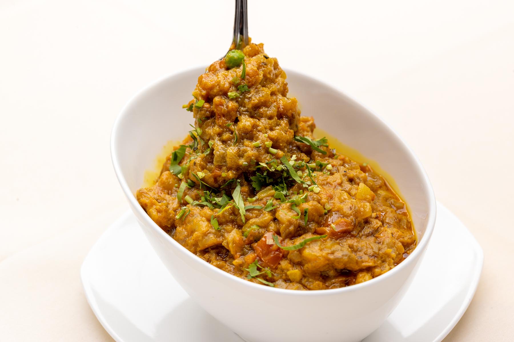 White bowl containing Indian-style vegetable curry garnished with chopped cilantro.