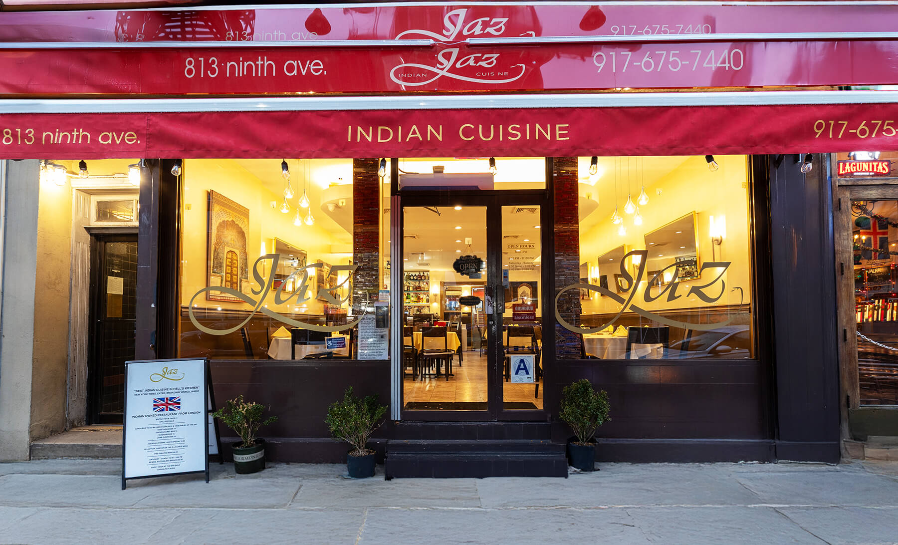 Front entrance of Jaz Jaz Indian Cuisine restaurant with red awning, glass door, and windows showing tables inside.