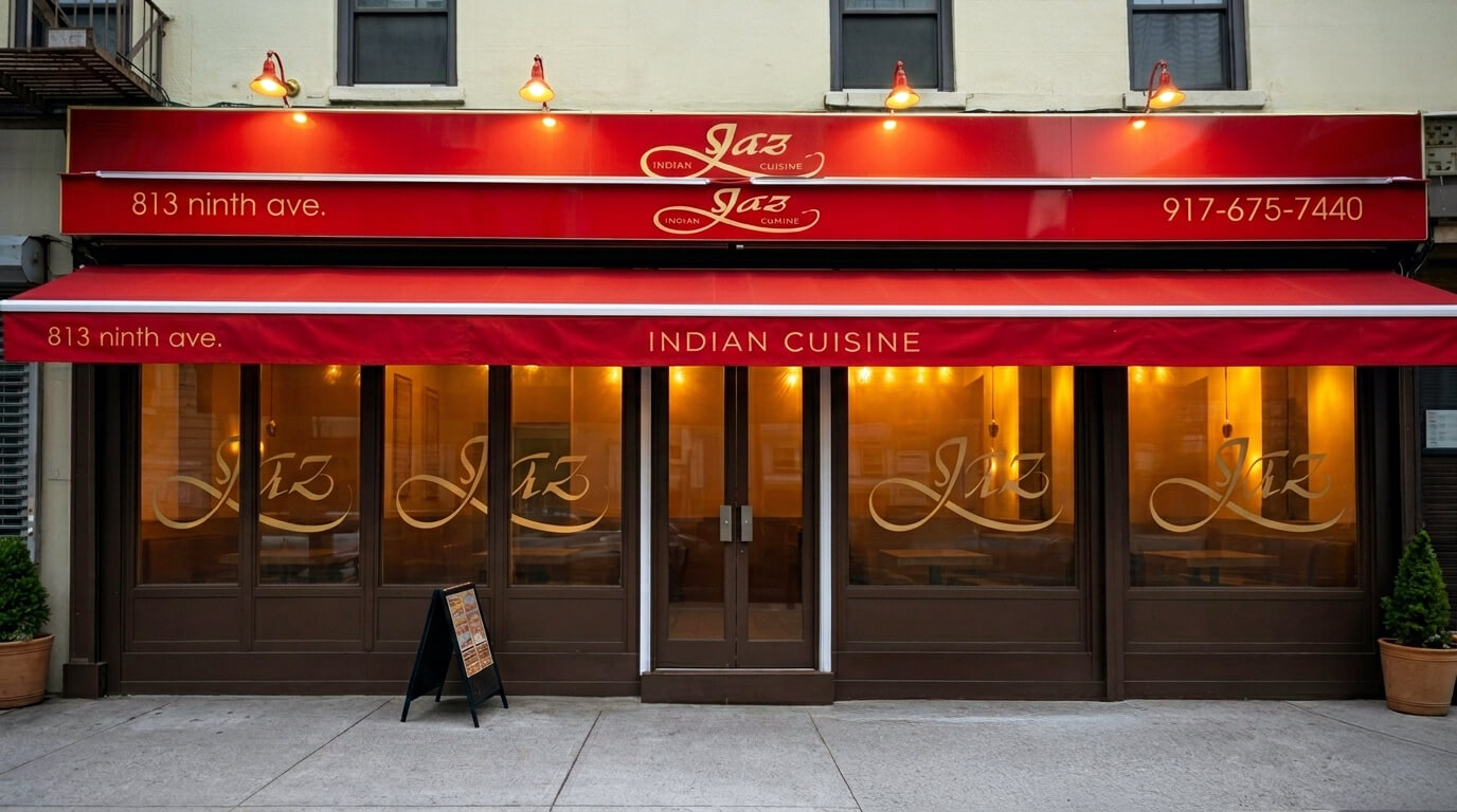 Front view of Jaz Indian Cuisine restaurant with red awning, illuminated signage, and large windows displaying the restaurant name.